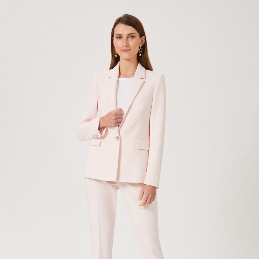 Woman in pale pink trouser suit